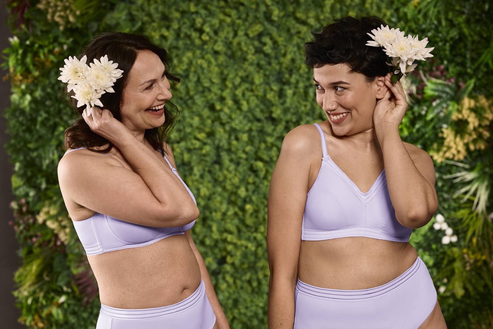 Deux femmes en lingerie lilas souriantes avec fleurs blanches, bien-être et confiance chez prothese-perruque-albi à Albi