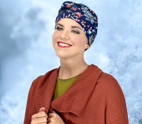 Femme souriante en turban fleuri bleu marine et veste chaude marron, ambiance douce, prothese-perruque-albi à Albi