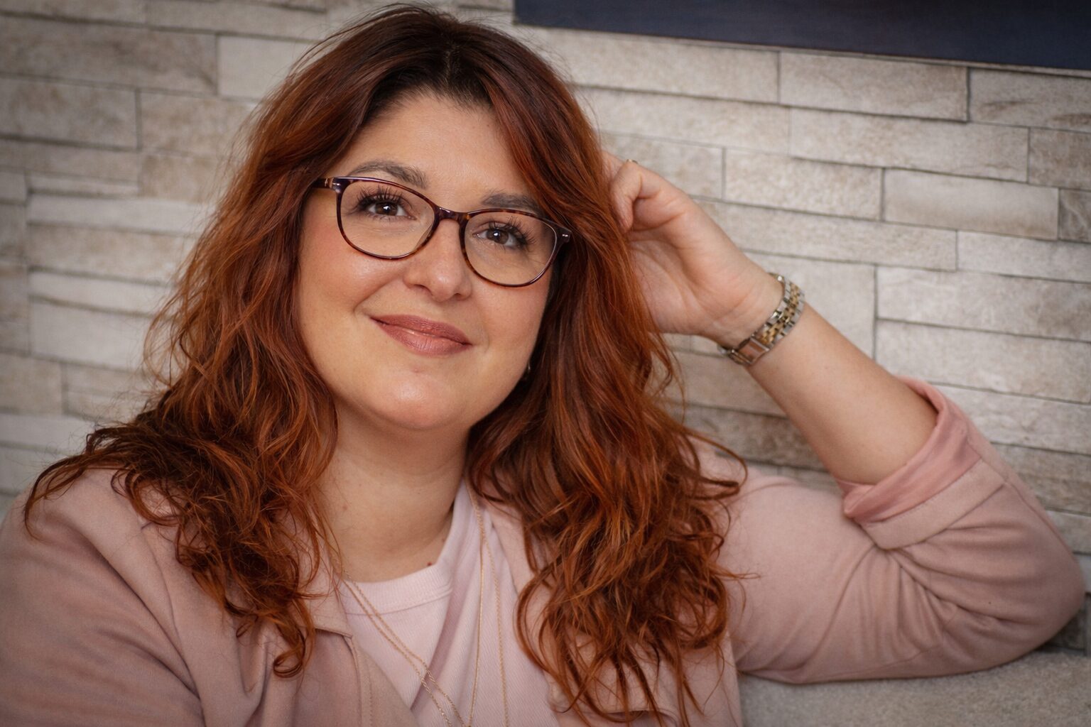 Femme rousse souriante avec lunettes, ambiance chaleureuse chez prothese-perruque-albi à Albi